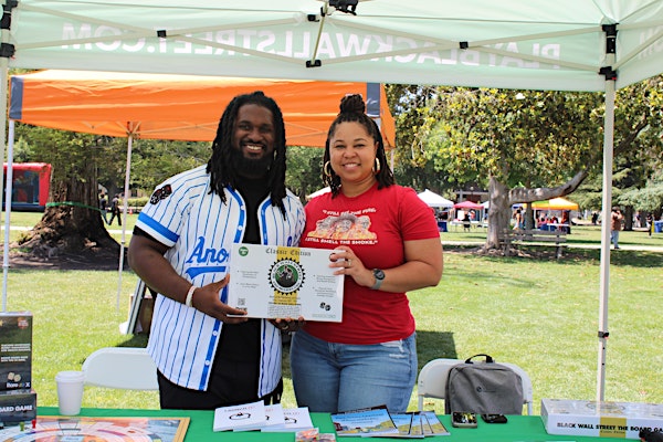 Man and woman standing next to each other holding a board game: Black Wall Street